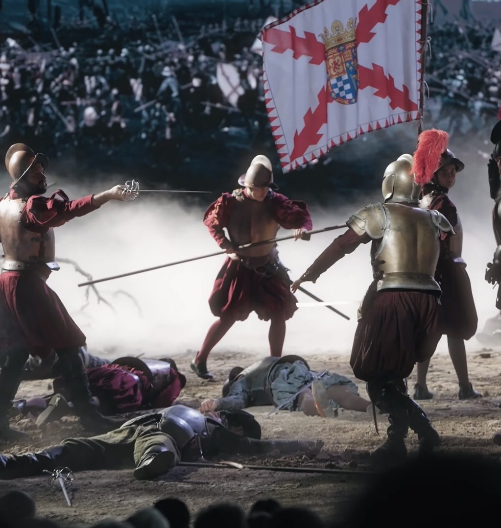 Battle scene on stage with soldiers in armour and a red and white flag